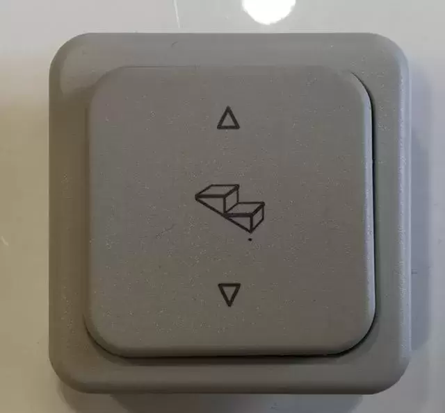 Interruptor CBE para peldaño eléctrico con marco, color gris claro.